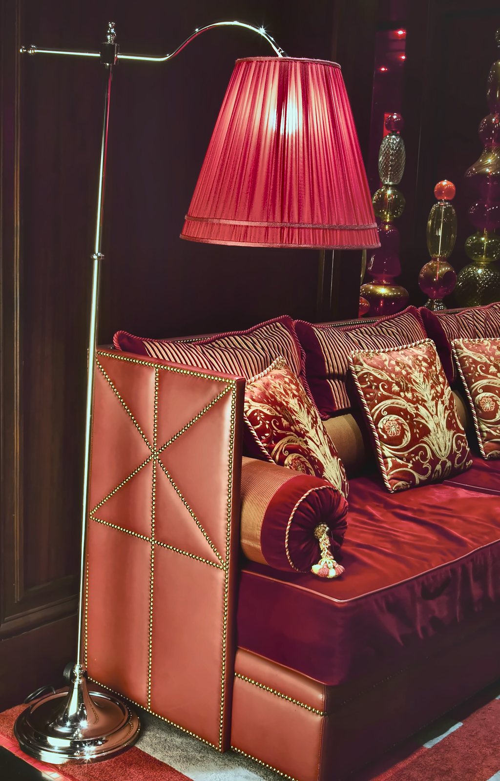 The floor lamp with red pleated silk shade beside the leather sofa in the Aleph relax room