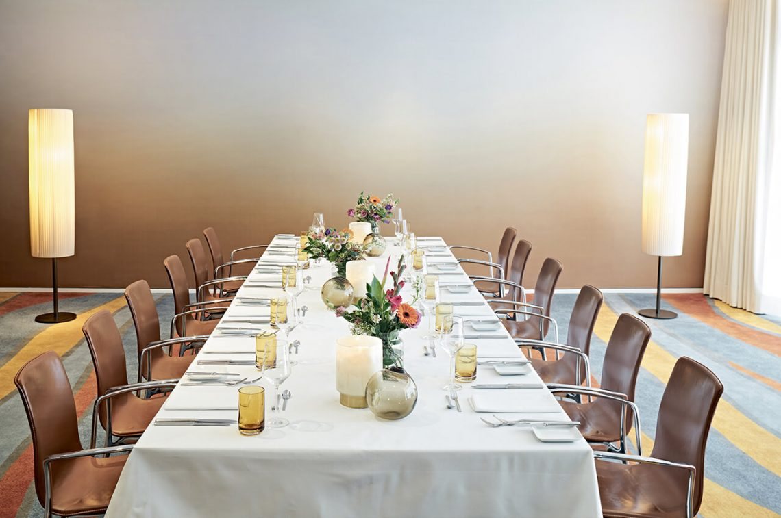 Two cylindrical pleated floor lamps flanking the long table in the SIDE Hotel private dining room
