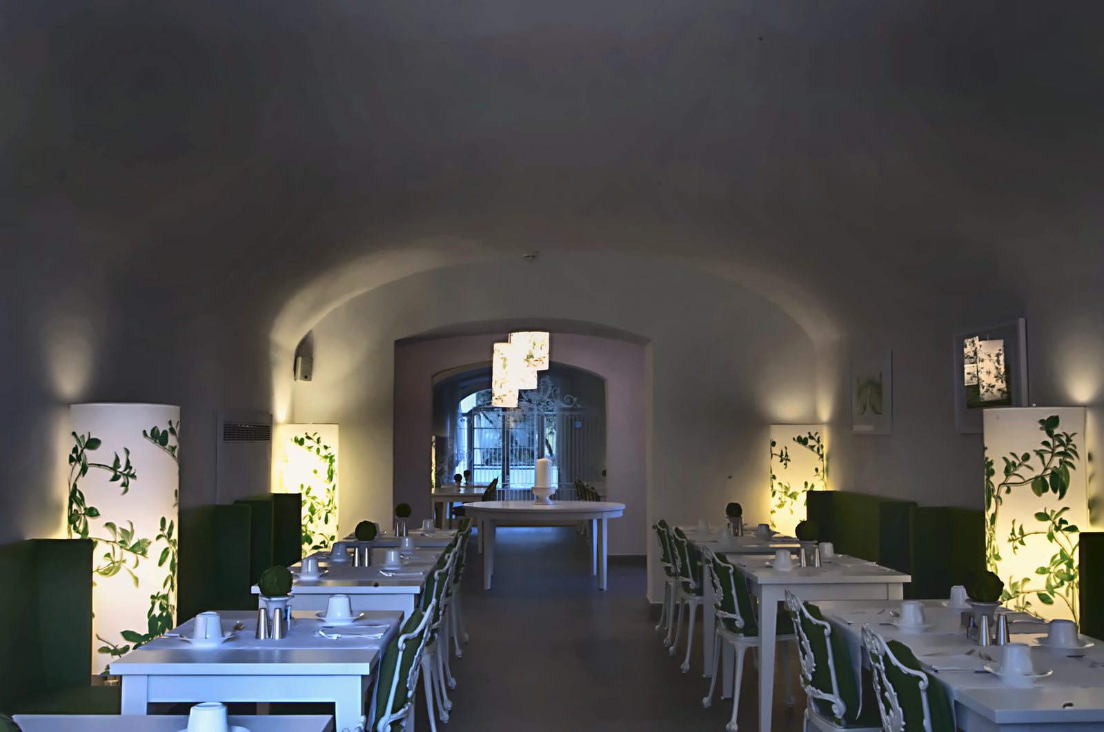 The restaurant under the vaults, with botanical-print light columns between the tables