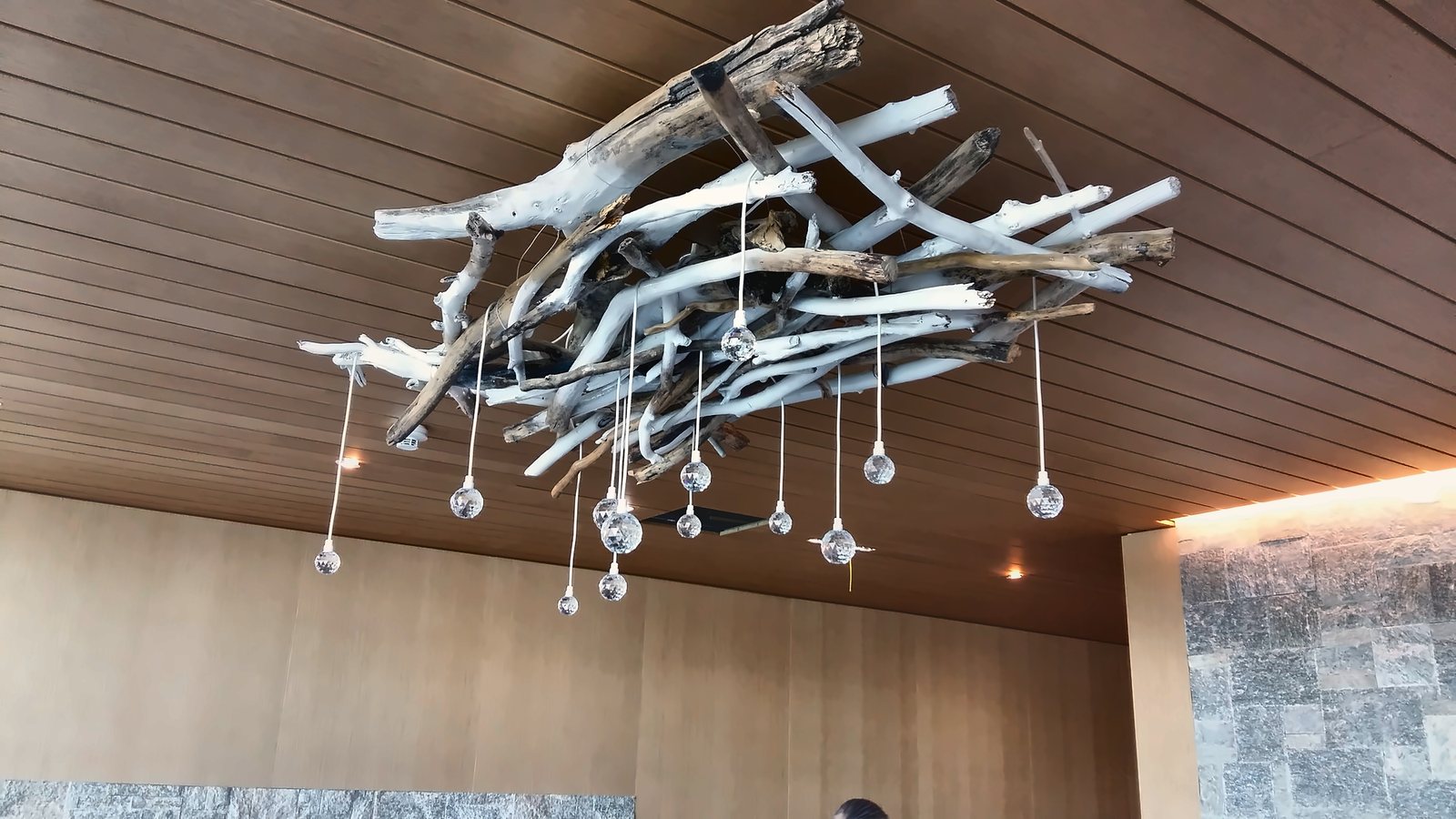 The cluster of glass drops hung from a branch structure, on the Alpine Spa's timber ceiling