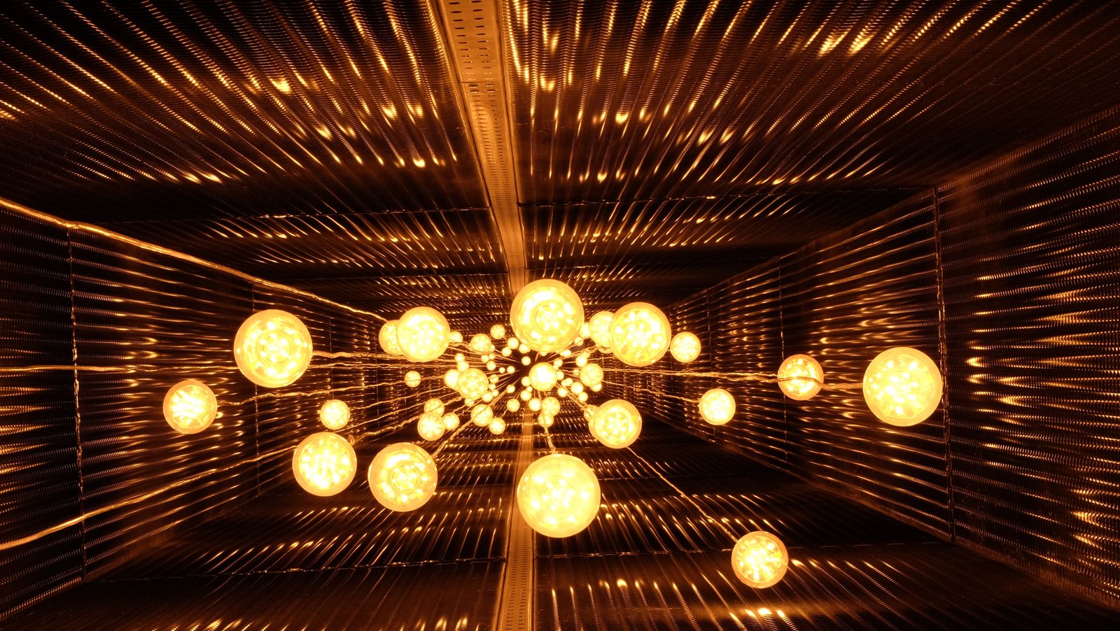 The room lined with orange slats, with the cluster of glowing globes at its centre