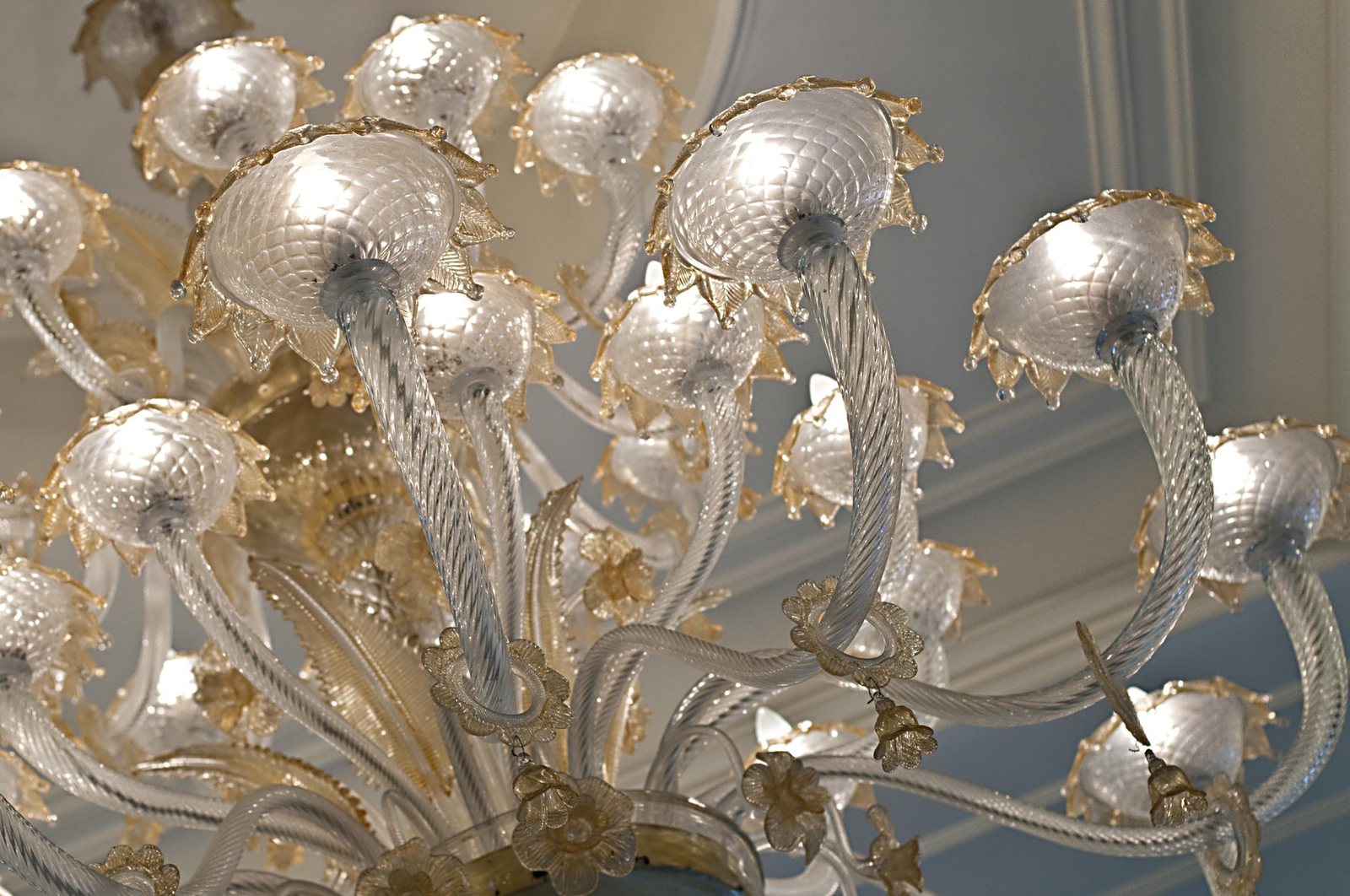 The chandelier arms close up: ribbed clear glass and cups with gilded detailing on the rims