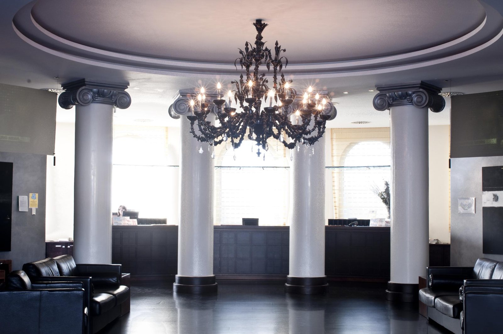 The black glass chandelier hung between the white columns of the lobby, above the dark floor