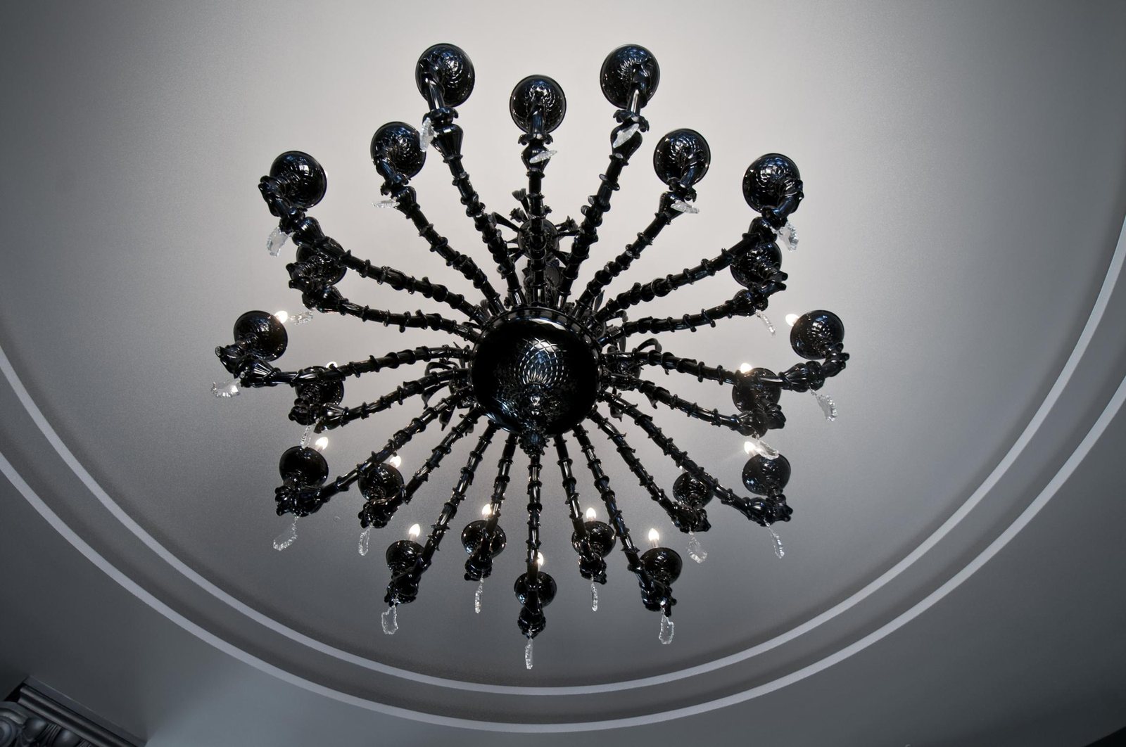The black glass chandelier seen from below: the arms open radially in the round ceiling recess
