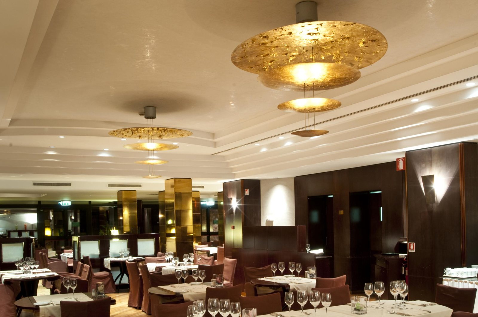 The restaurant laid for service, with the gilded discs suspended below the ceiling