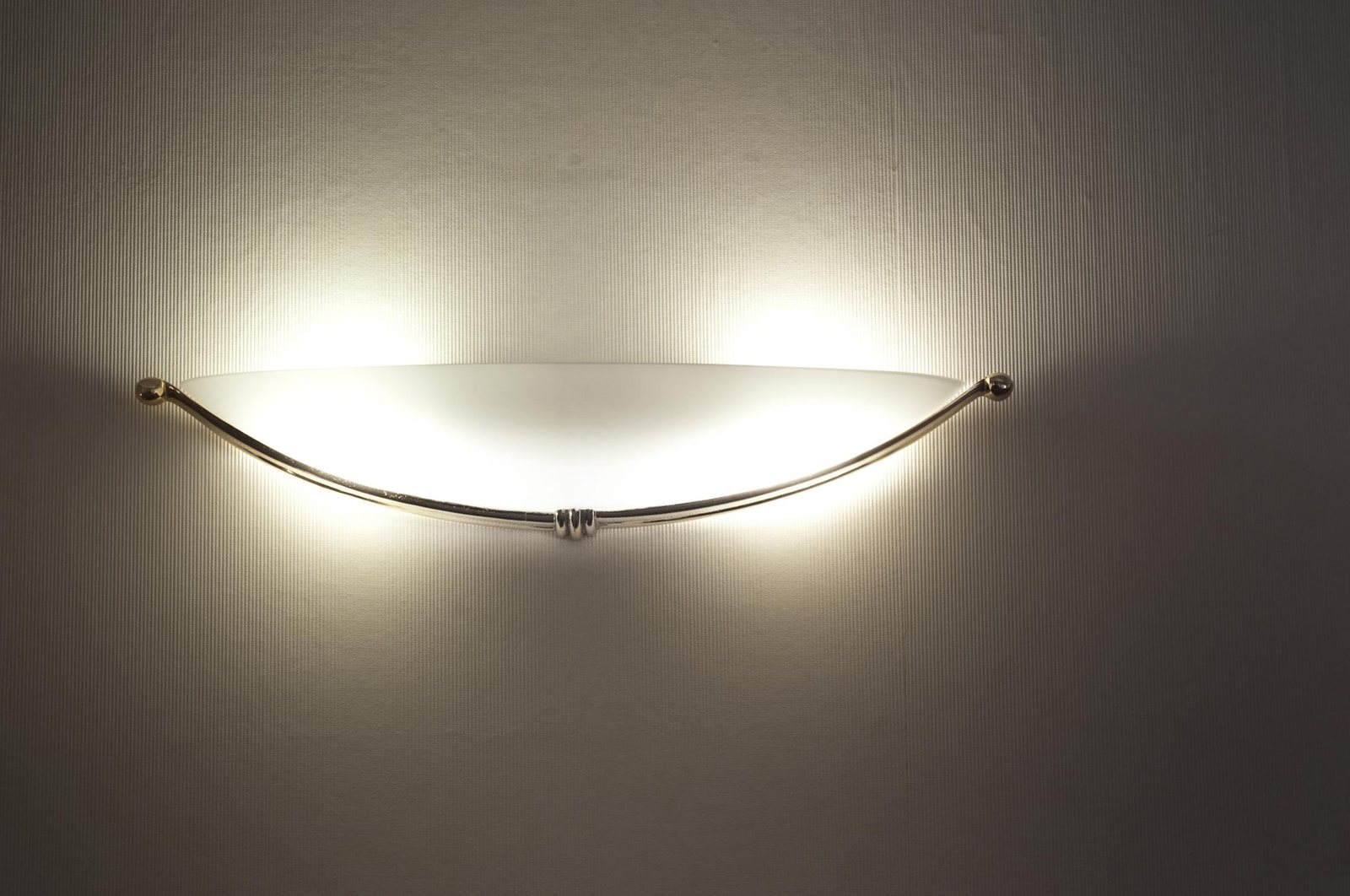 The hull-shaped opal glass wall light, held by a slim metal bow