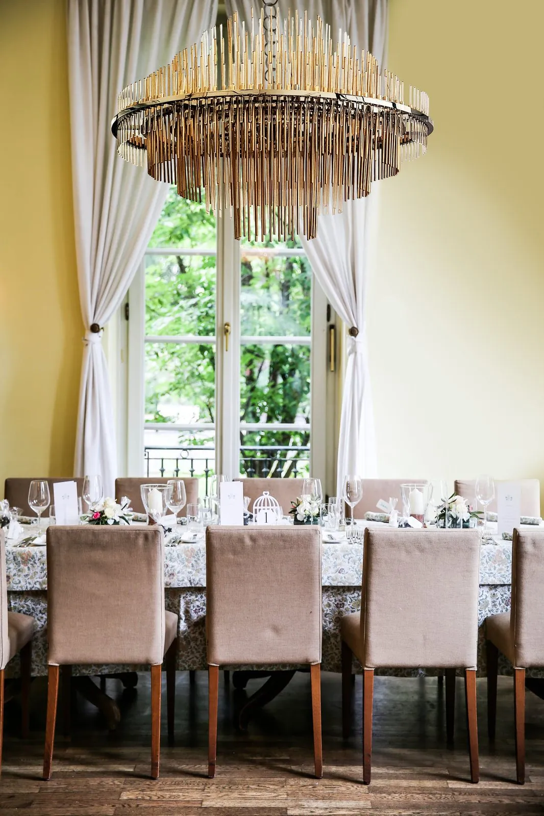 The GF200 chandelier lit above the laid table, in front of the window onto the garden