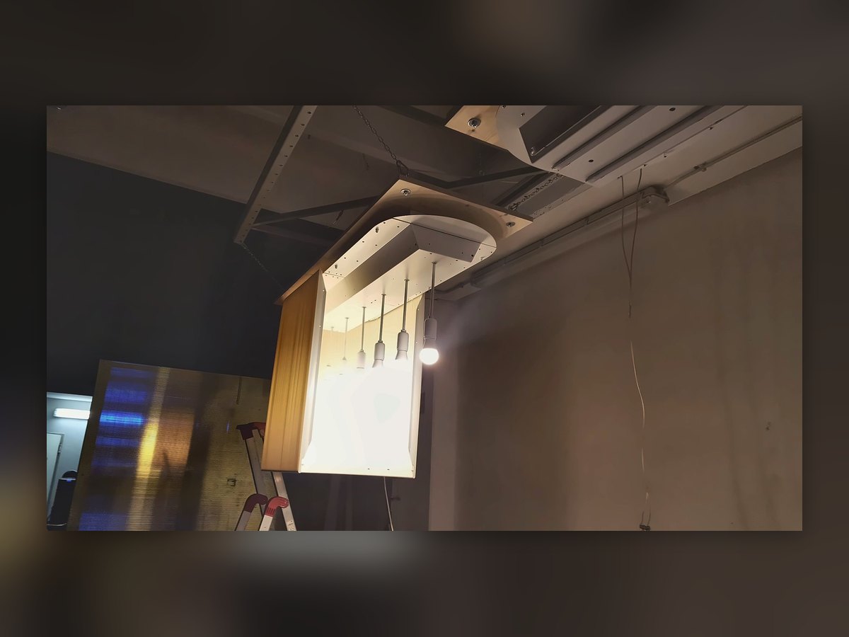 A pleated shade lit for testing in our workshop, hung from the shed structure