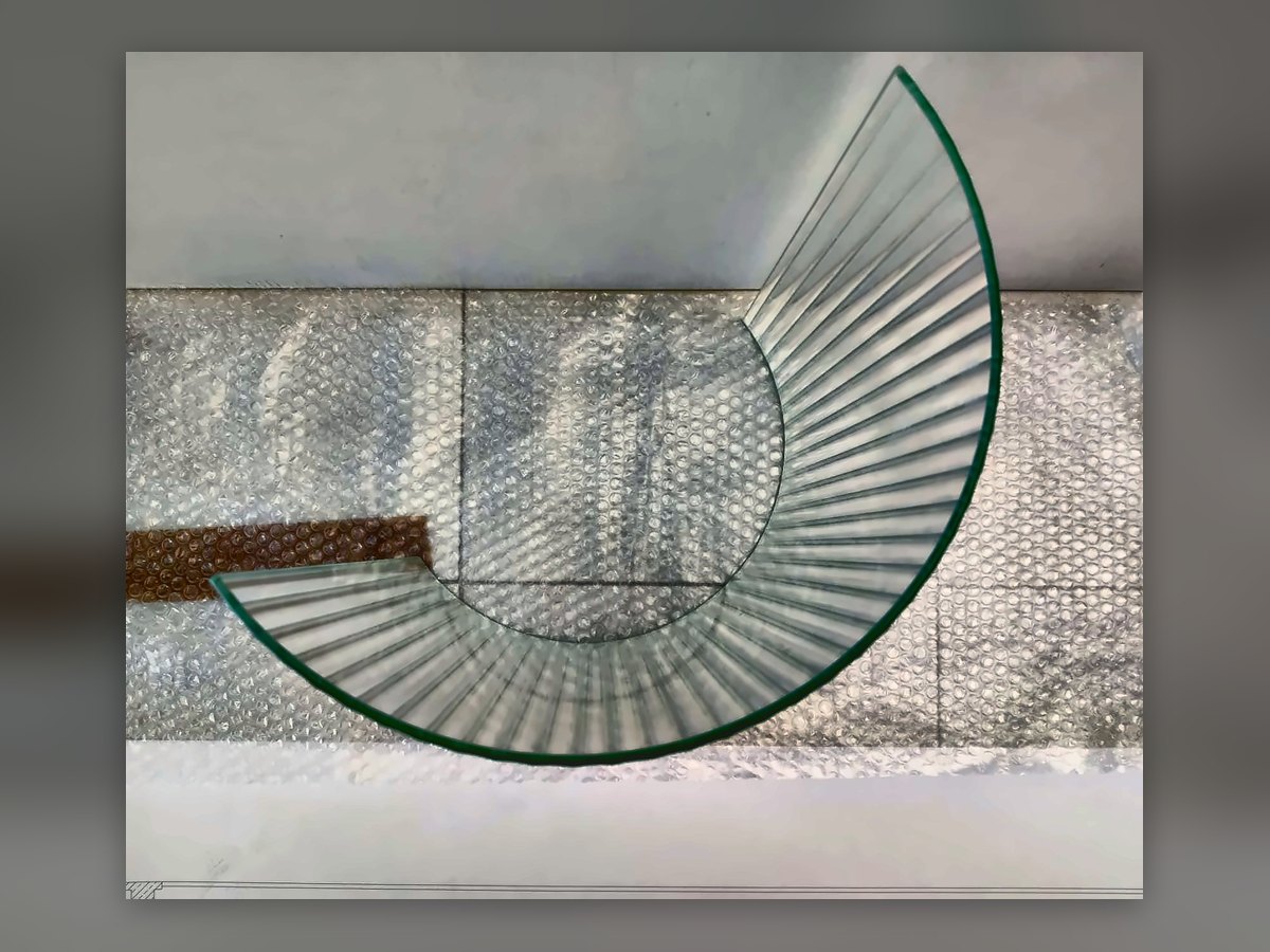 A curved fluted glass panel resting on bubble wrap after bending