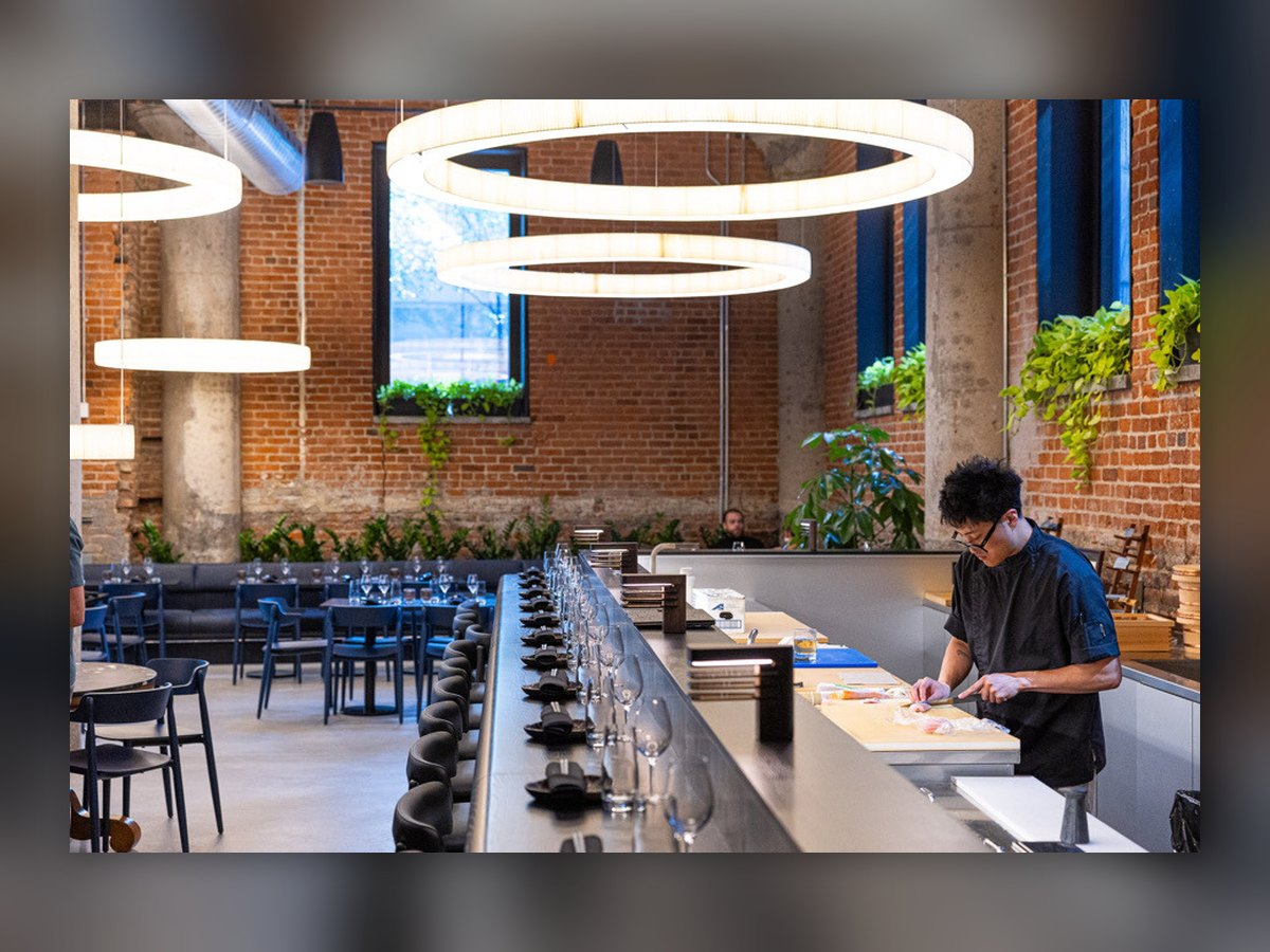 The omakase counter with the chef at work, under the pair of pleated rings
