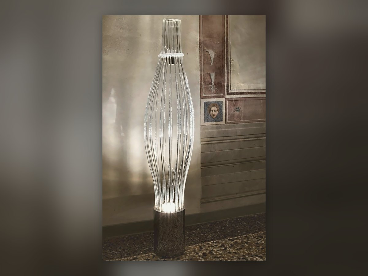 Vase-shaped floor lamp built from vertical glass canes, against the frescoed wall