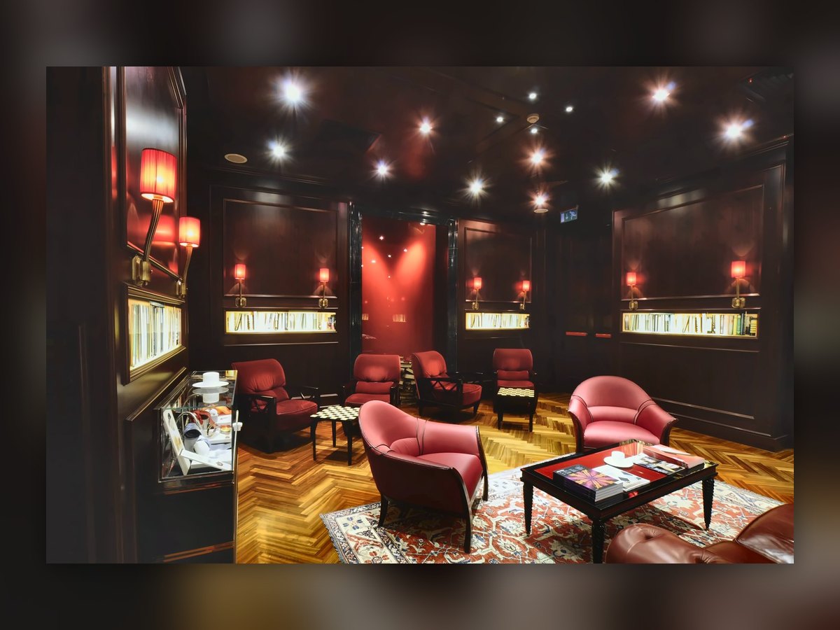 The Aleph lounge with red armchairs, book niches and red pleated wall lights along the dark wood panelling