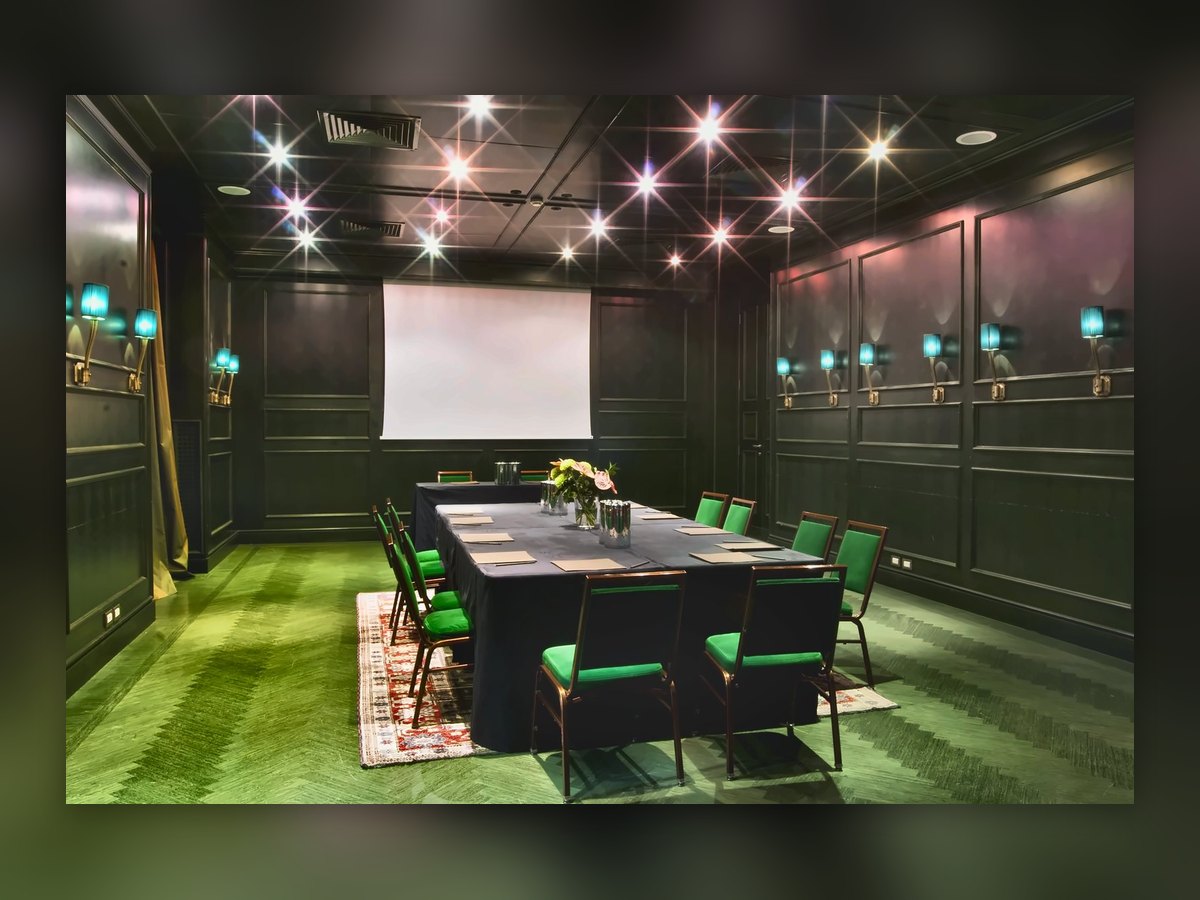The Aleph meeting room: green carpet, dark panelling and turquoise wall lights along the walls