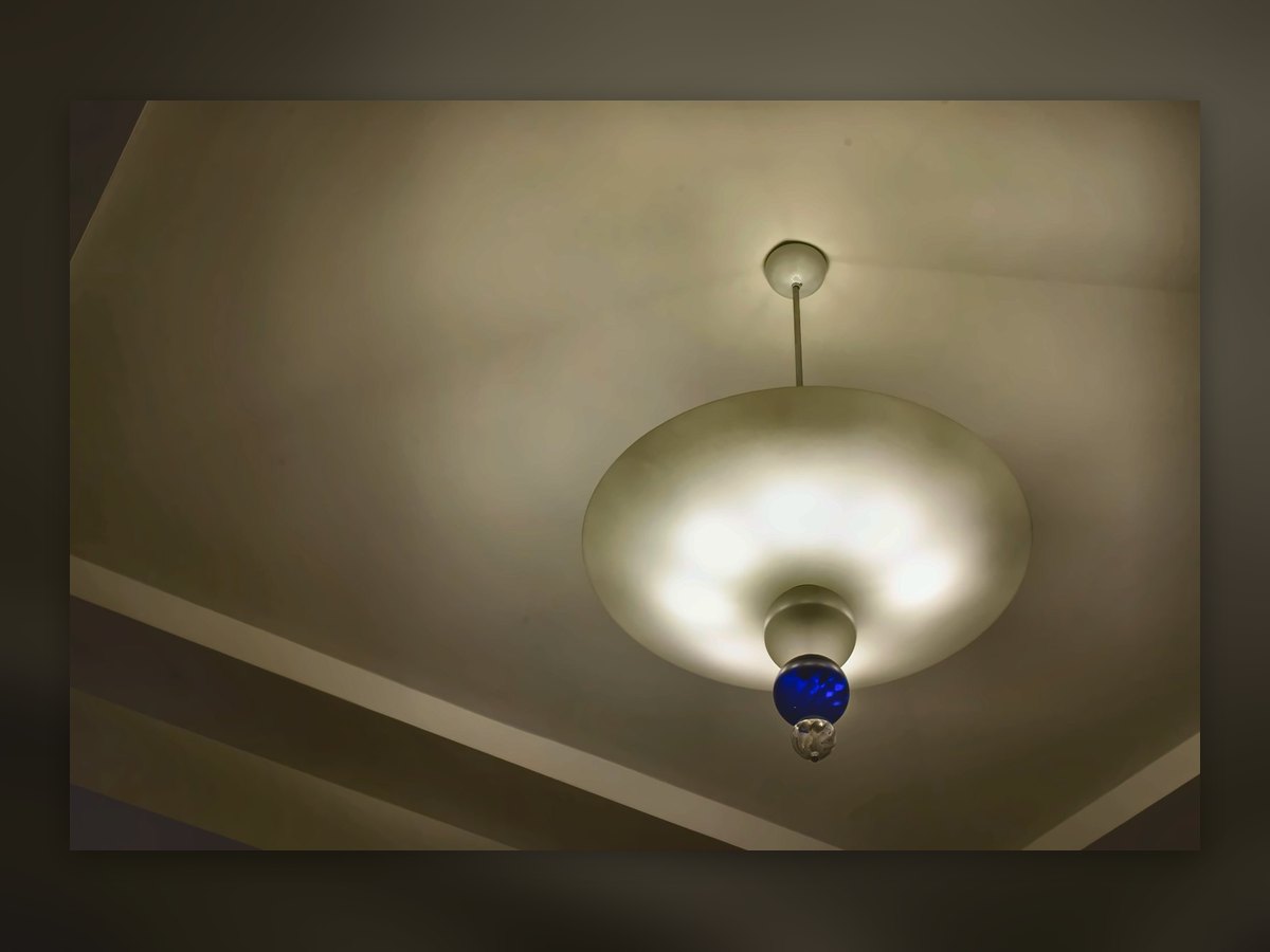 White glass disc ceiling light with a blue glass finial, seen from below