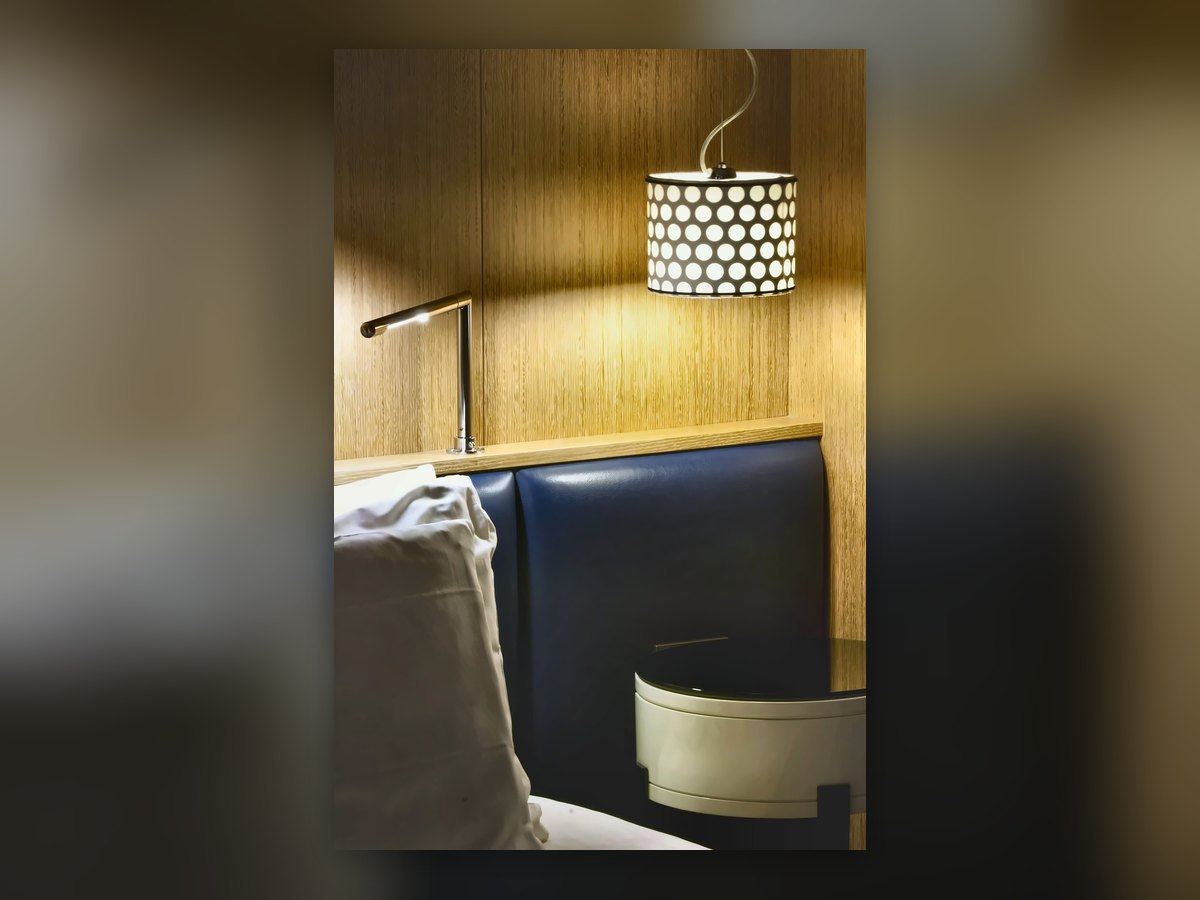 Drum pendant with a perforated dotted shade, above the bedroom banquette