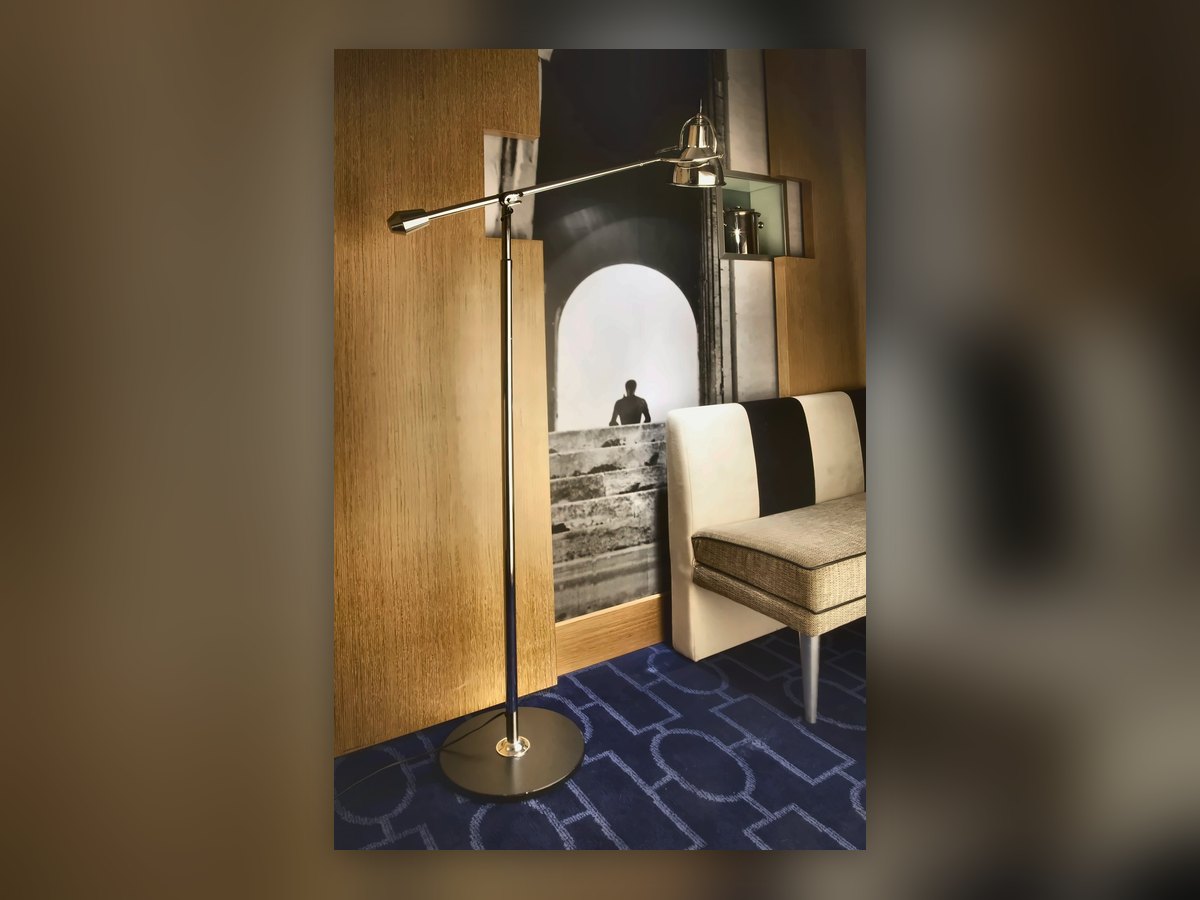 Floor lamp with an articulated chrome arm in the corridor with blue carpet