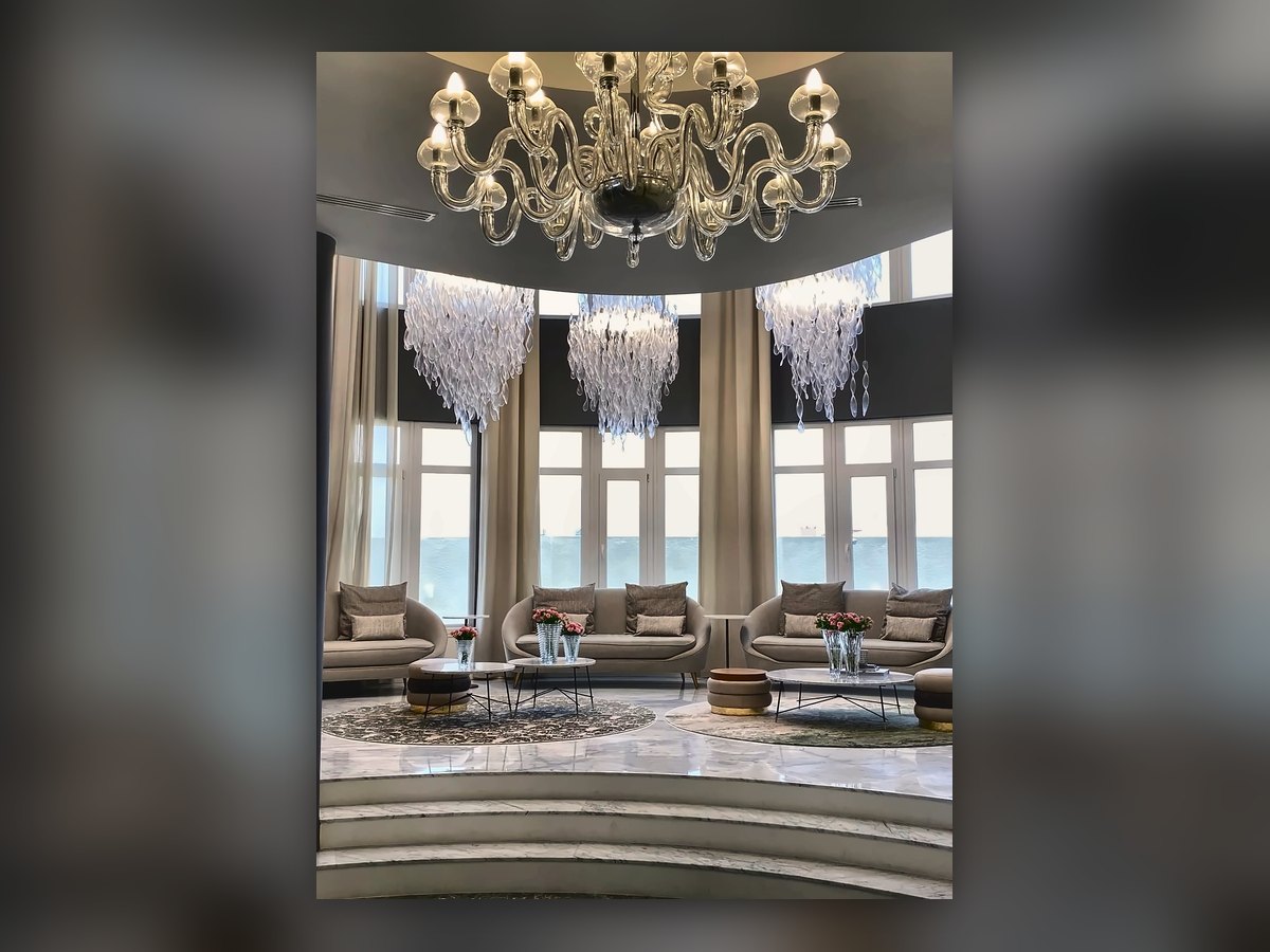 La salle attenante avec le lustre doré à bras, et les cascades de verre en arrière-plan