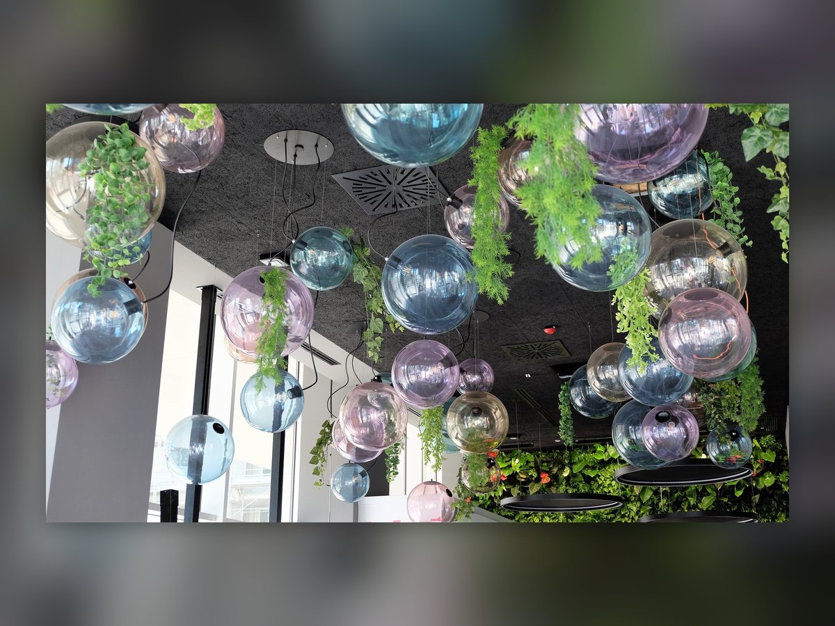 The cluster of coloured and mirrored glass spheres seen from below, with plants trailing between them