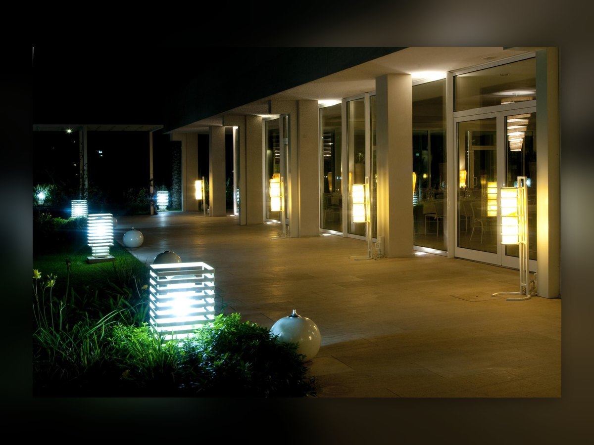 The portico at night: the lit bollard in the foreground and the row of lights along the glazing