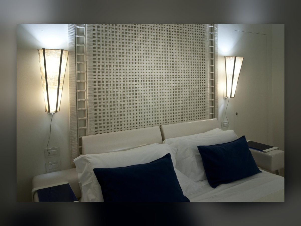 The two tapered wall lights either side of the headboard, on the room's perforated panel