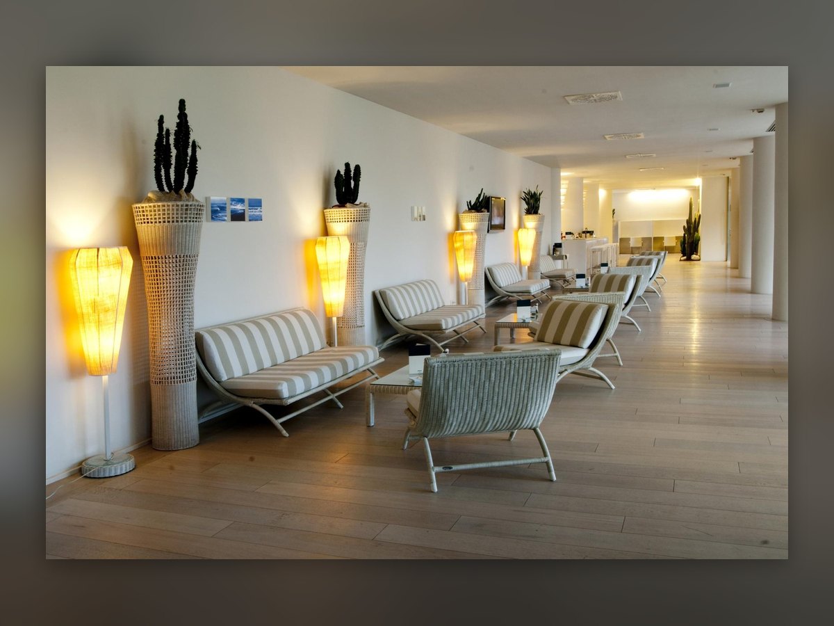 The corridor with its glowing floor lamps and perforated planters holding cacti, along the seating