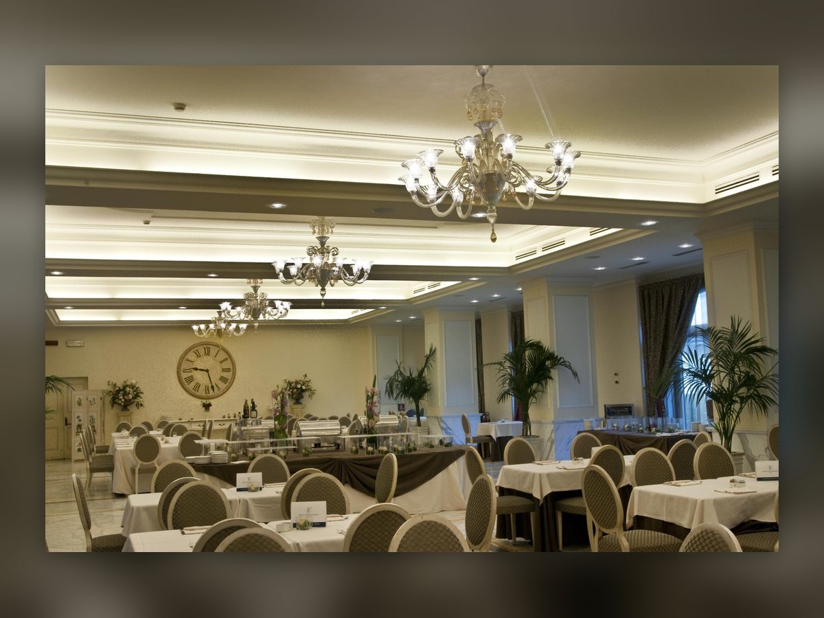 The banqueting room laid for service, blown glass chandeliers aligned under the coffered ceiling