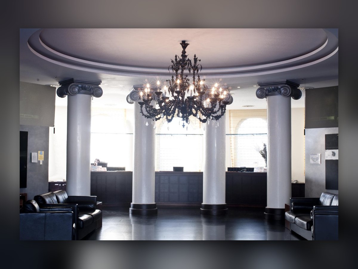 The black glass chandelier hung between the white columns of the lobby, above the dark floor