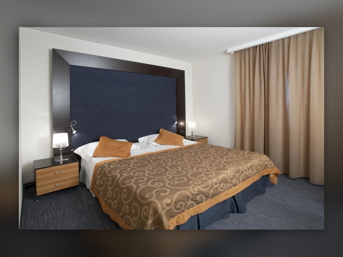 The guest room with its blue upholstered headboard and the two reading lights either side of the bed
