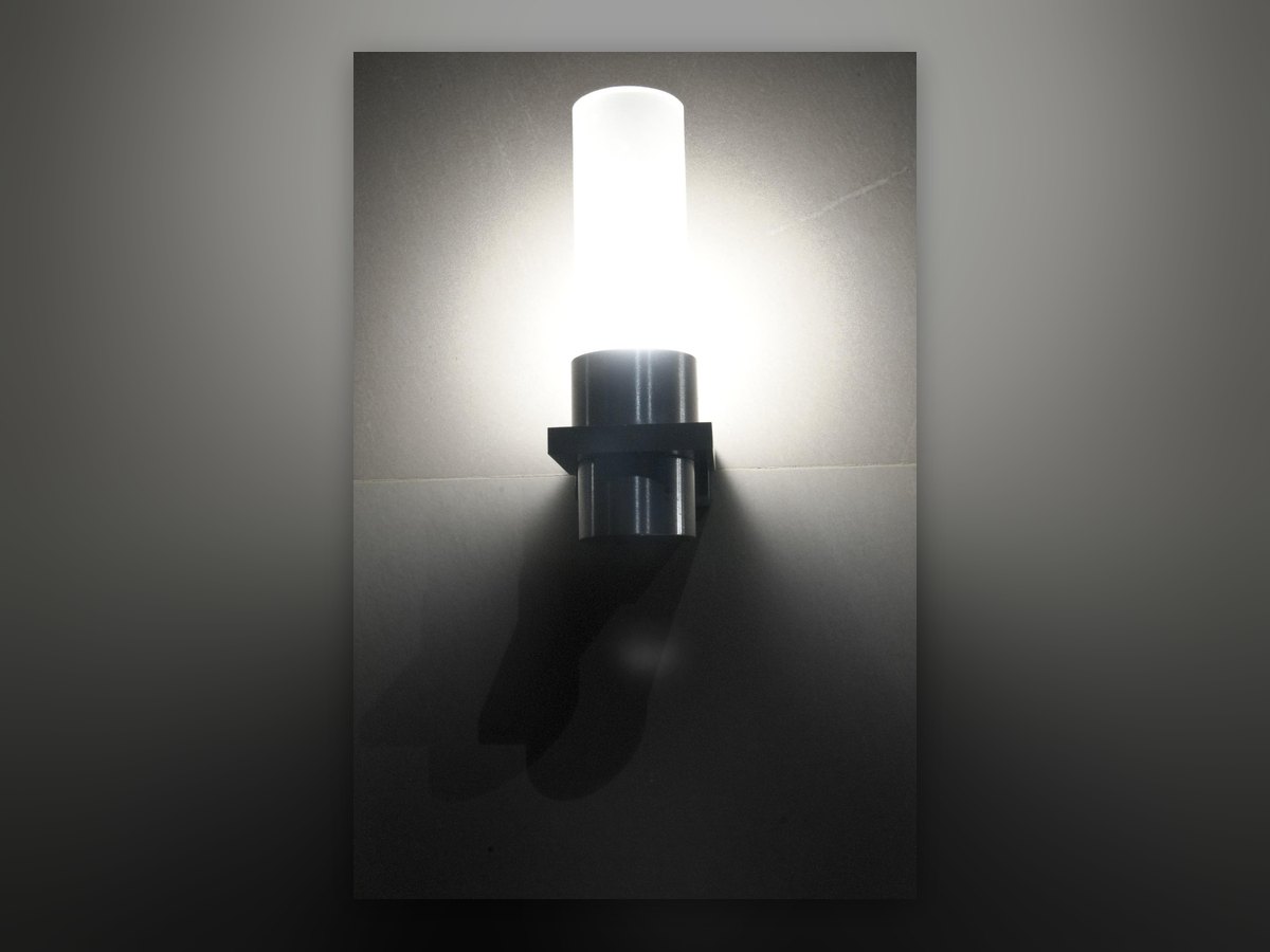 The wall light lit: an opal glass cylinder on a chrome bracket