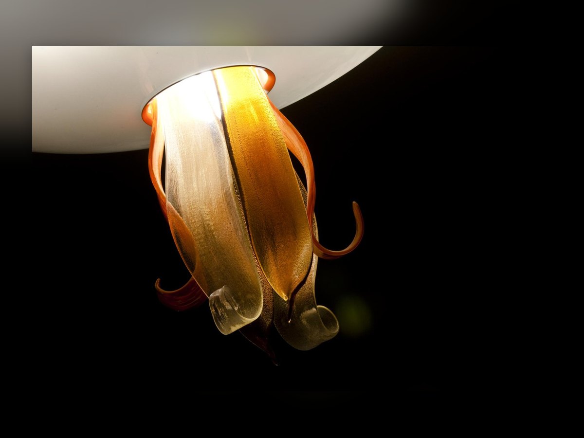 The amber glass flower beneath the bowl, its petals curling upwards