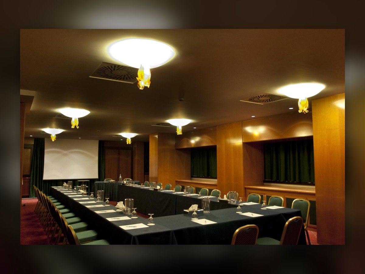 The meeting room with its table laid and the opal bowls lit on the ceiling
