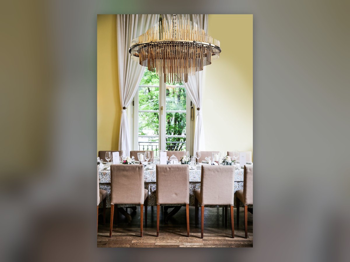 The GF200 chandelier lit above the laid table, in front of the window onto the garden