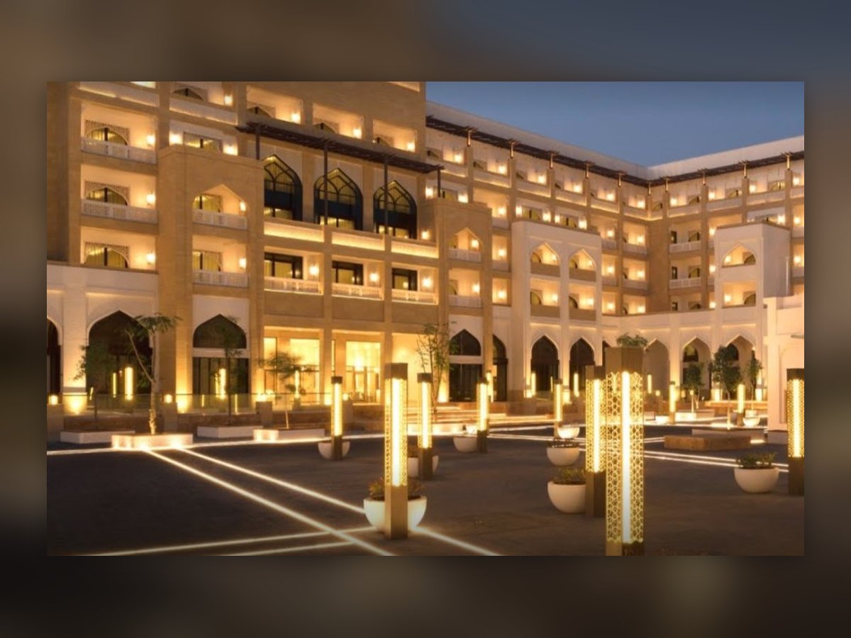 The courtyard at dusk, gilded perforated columns lit among the planters