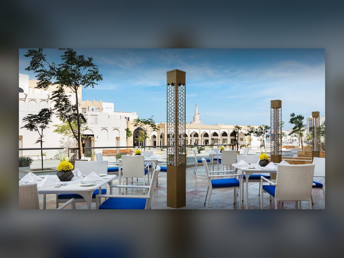 The terrace by day, gilded perforated columns standing between the tables