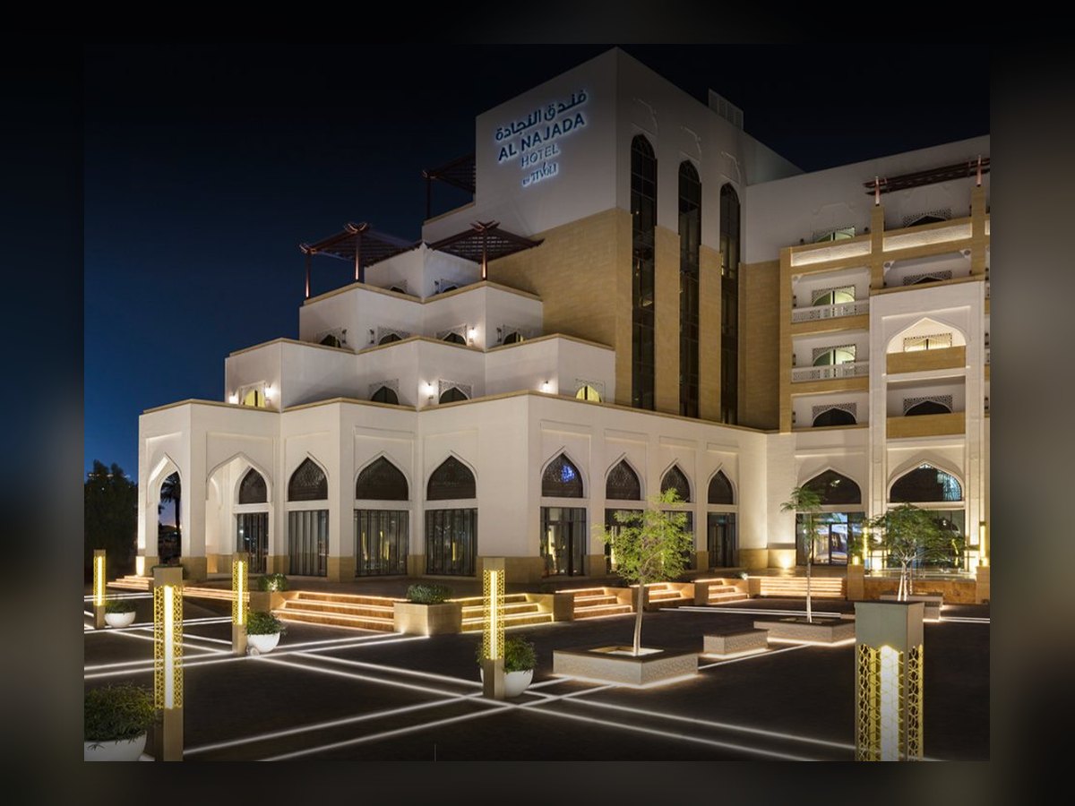 The facade at night, arches lit and gilded columns standing in the forecourt