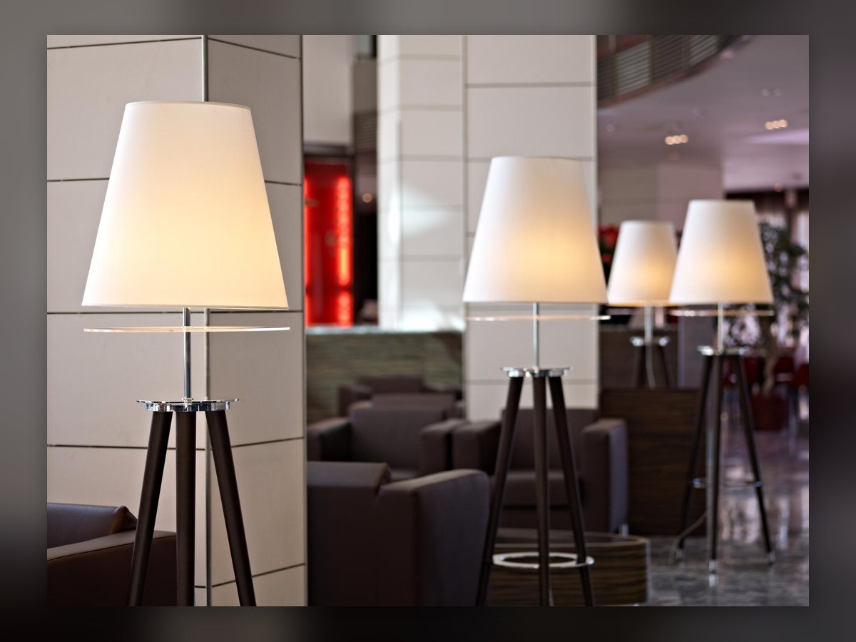 The lobby of the Antony Palace Hotel: four tripod floor lamps with white shades among the dark armchairs and the pillars