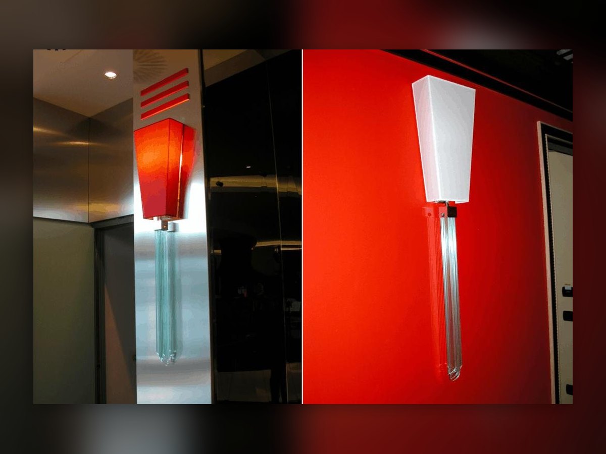The wall lamp of the UNA Hotel Malpensa in two views: red shade on the metal-clad pillar, white on the red wall, pendant of crystal lozenges