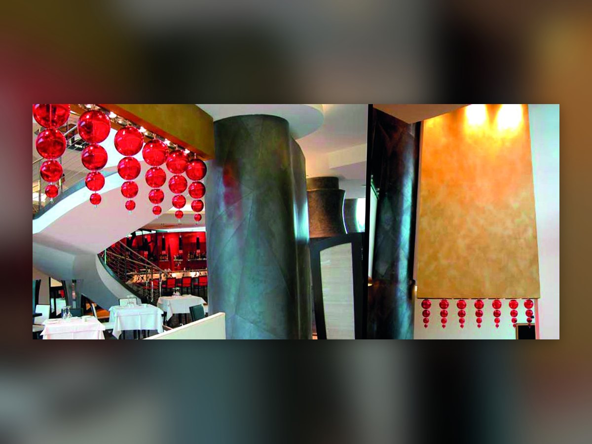 Die roten mundgeblasenen Glaskugeln des UNA Hotel Malpensa in zwei Ansichten: über der Wendeltreppe und in einer Reihe unter einer vergoldeten Wandfläche
