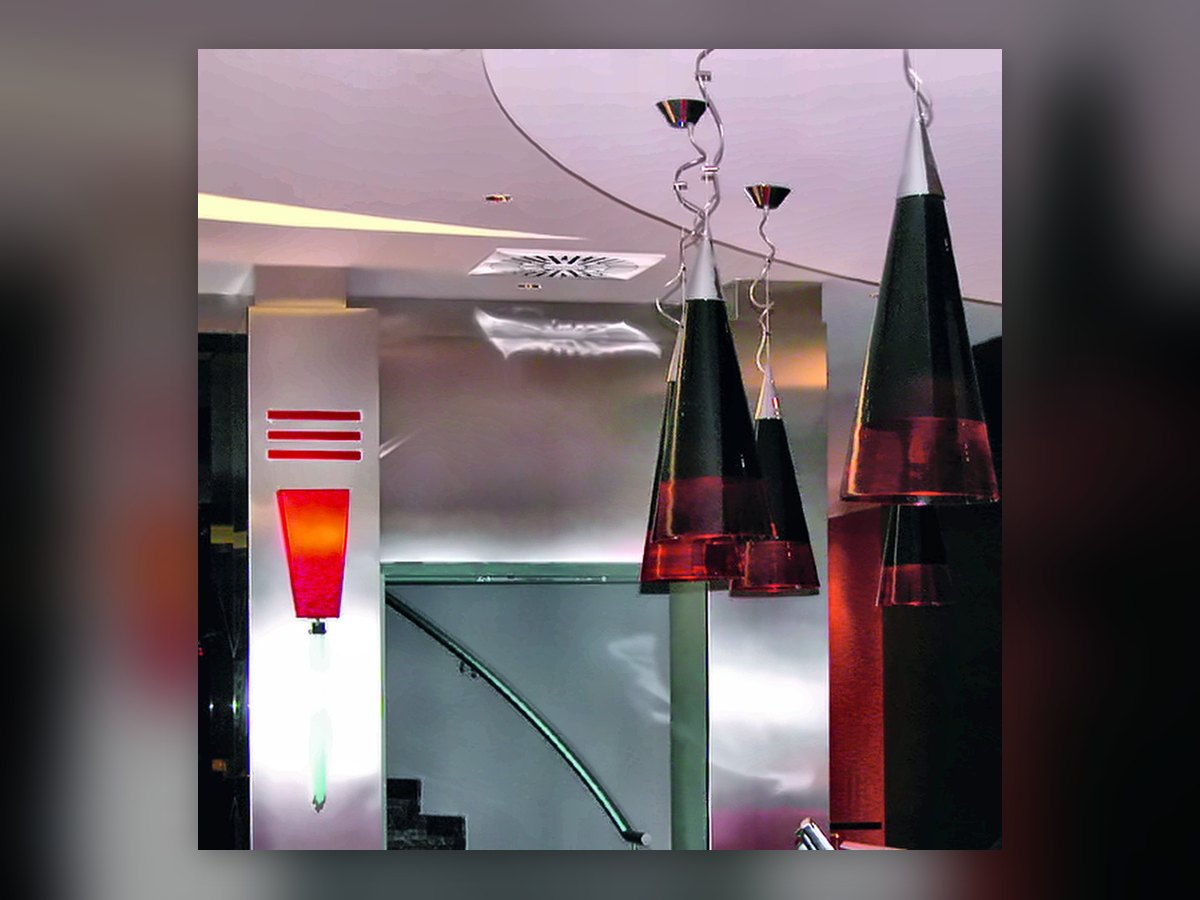 Die schwarz-roten Kegel aus mundgeblasenem Glas über der Rezeption des UNA Hotel Malpensa und die rote Wandleuchte am Stahlpfeiler